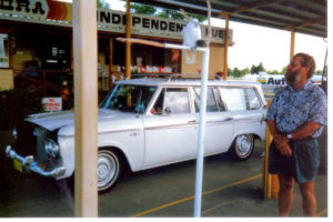 Neville standing in front of his Studebaker Wagonaire looking at a white Cockatoo